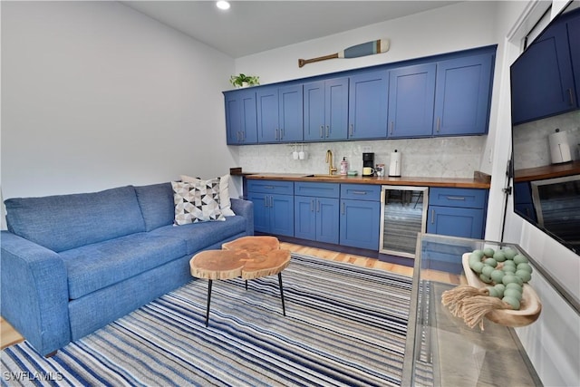 living room with light wood finished floors, wine cooler, indoor wet bar, and recessed lighting