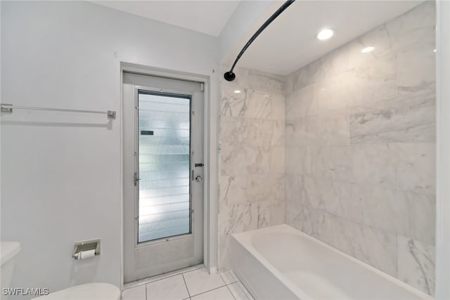 bathroom featuring tiled shower / bath, toilet, and tile patterned flooring