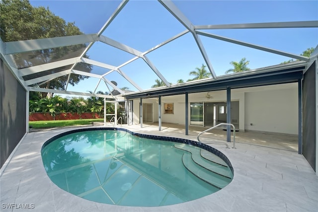 view of pool with glass enclosure, ceiling fan, and a patio