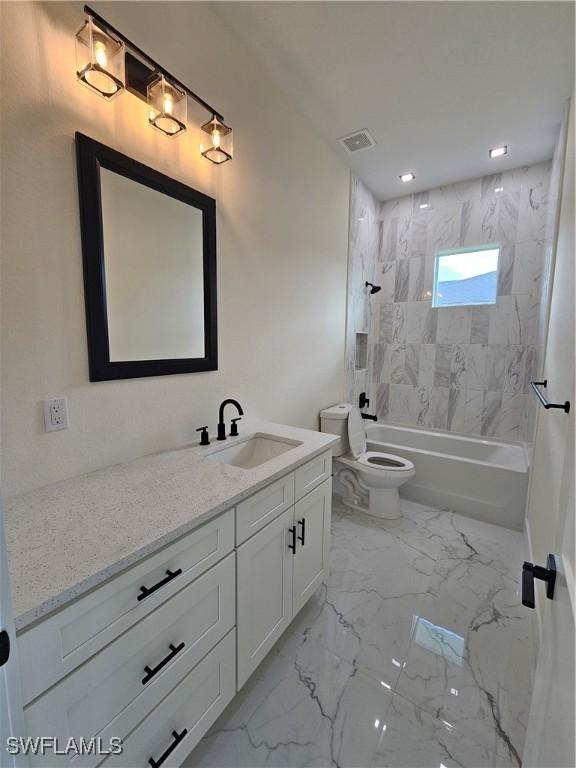 full bathroom featuring vanity, tiled shower / bath combo, and toilet