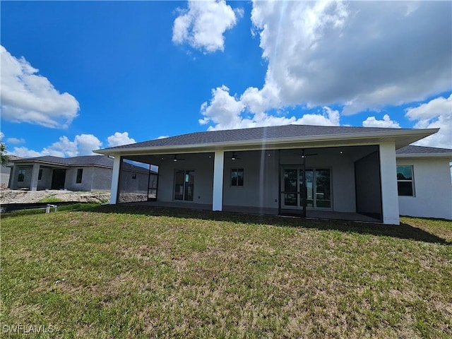 back of property featuring ceiling fan and a lawn