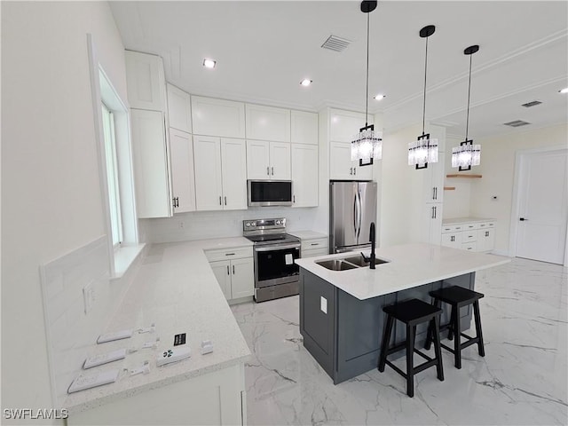 kitchen featuring appliances with stainless steel finishes, sink, a center island with sink, white cabinets, and hanging light fixtures