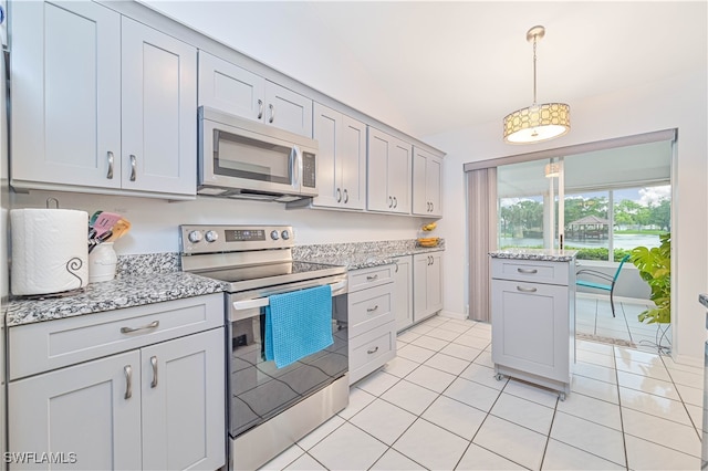 kitchen featuring light stone countertops, light tile patterned floors, stainless steel appliances, and vaulted ceiling