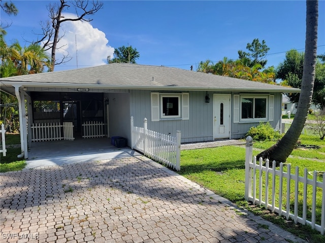 single story home with an attached carport, roof with shingles, fence, decorative driveway, and a front lawn