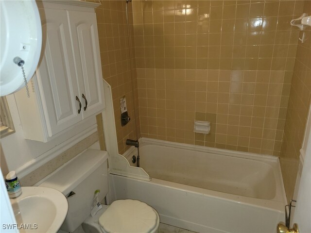 full bathroom featuring sink, tiled shower / bath combo, and toilet