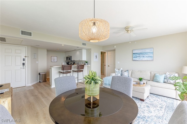 dining area with light wood-type flooring and ceiling fan