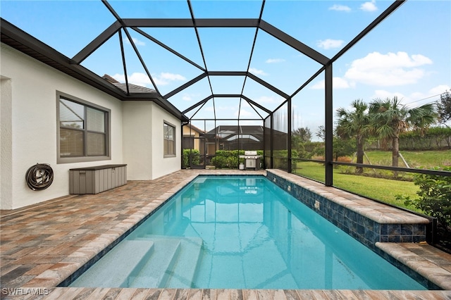 view of swimming pool with a patio, a lawn, and glass enclosure