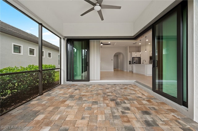 unfurnished sunroom with ceiling fan