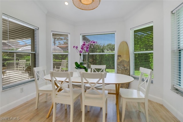 dining area with light hardwood / wood-style flooring and ornamental molding