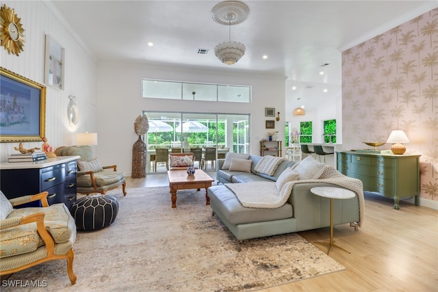 living room featuring light wood-type flooring, crown molding, and an inviting chandelier