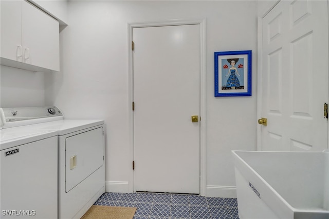 clothes washing area featuring washing machine and clothes dryer, cabinets, and light tile patterned floors