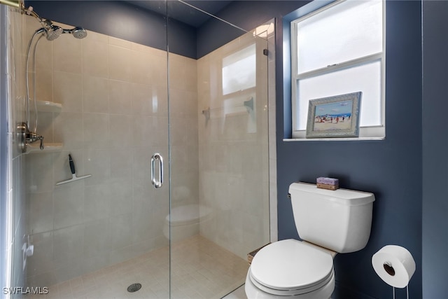 bathroom featuring toilet and a shower with shower door