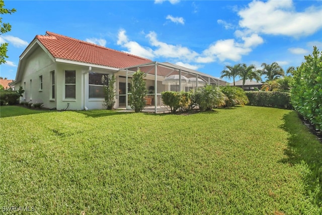 rear view of property featuring glass enclosure and a yard