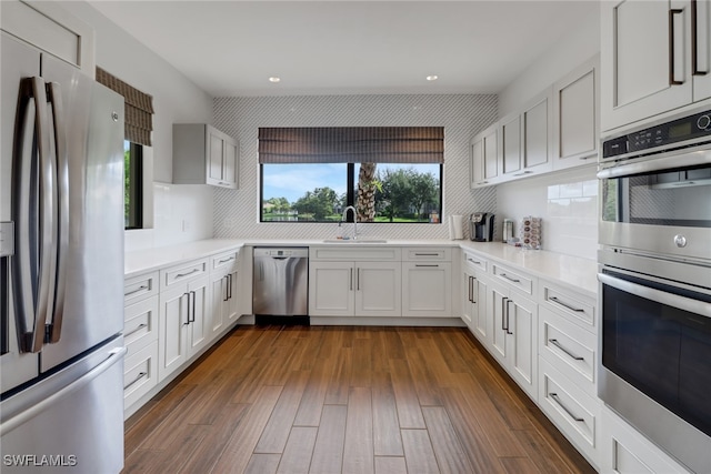 kitchen with tasteful backsplash, white cabinetry, dark hardwood / wood-style floors, and stainless steel appliances