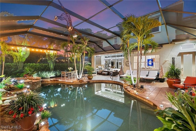 pool at dusk featuring outdoor lounge area, glass enclosure, and a patio area