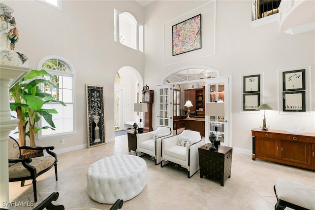 living area featuring french doors, a towering ceiling, and light tile patterned floors