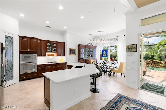 kitchen featuring a center island with sink, ornamental molding, sink, and appliances with stainless steel finishes