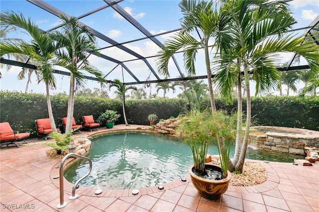 view of swimming pool featuring pool water feature, glass enclosure, a patio, and a hot tub