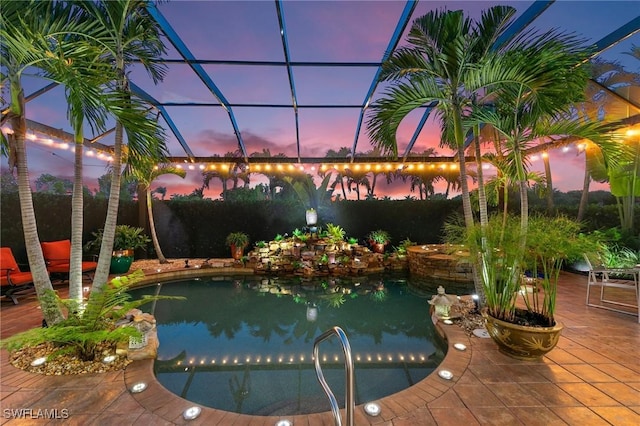 pool at dusk featuring a patio area, a lanai, and a water view