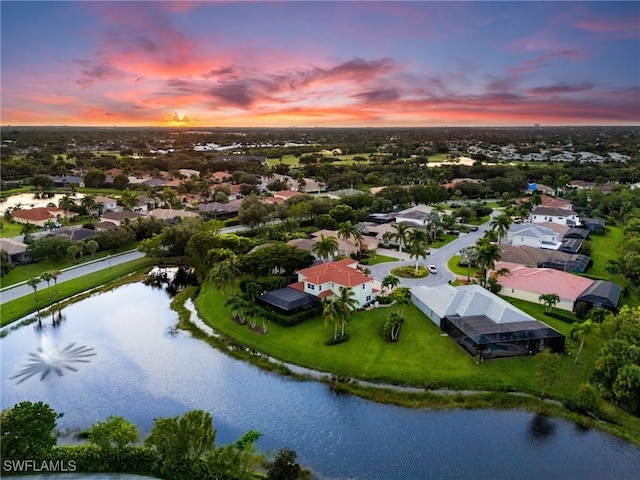 aerial view at dusk featuring a water view