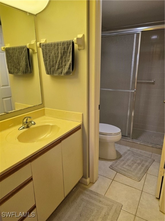 bathroom featuring tile patterned flooring, an enclosed shower, vanity, and toilet