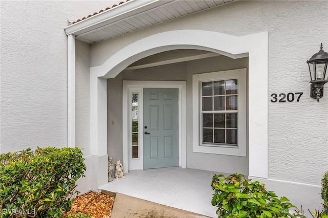 entrance to property featuring a tile roof and stucco siding