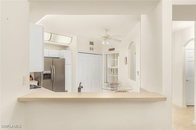 kitchen featuring ceiling fan, stainless steel refrigerator with ice dispenser, white cabinets, kitchen peninsula, and light tile patterned flooring