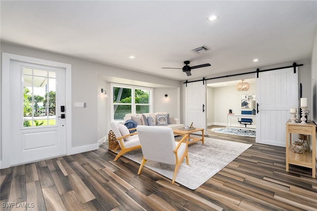 living room with a barn door, ceiling fan, and dark hardwood / wood-style floors