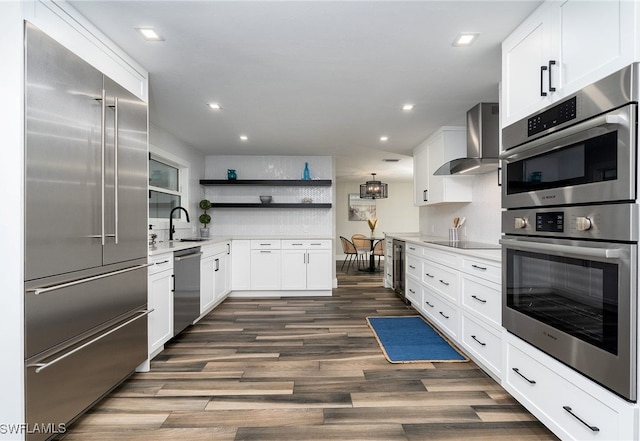 kitchen featuring white cabinets, stainless steel appliances, sink, wall chimney range hood, and dark hardwood / wood-style floors