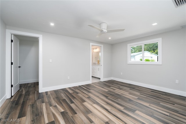 unfurnished bedroom featuring connected bathroom, dark hardwood / wood-style flooring, ceiling fan, a closet, and a spacious closet