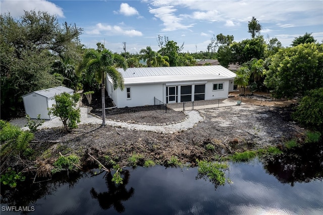 rear view of house featuring a storage unit, a water view, and a patio