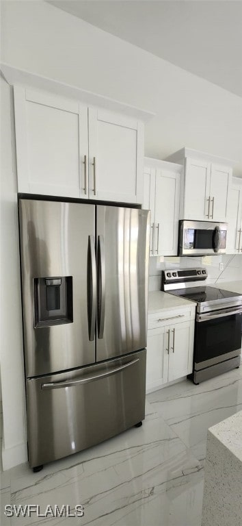 kitchen with appliances with stainless steel finishes, white cabinetry, and light stone counters