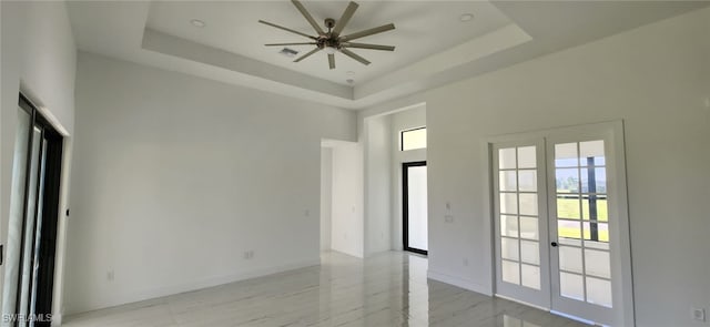 spare room with a tray ceiling, french doors, and ceiling fan