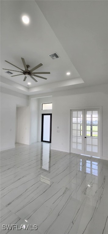 spare room with a raised ceiling, ceiling fan, and french doors