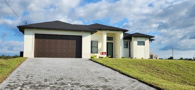 prairie-style house featuring a garage and a front lawn