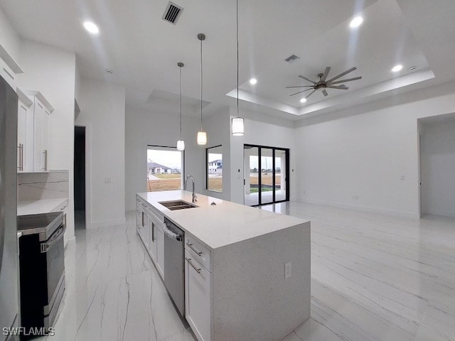 kitchen with appliances with stainless steel finishes, an island with sink, sink, white cabinetry, and ceiling fan