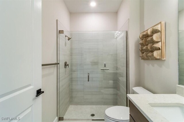 bathroom featuring a shower with shower door, vanity, and toilet