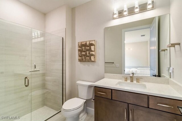 bathroom featuring vanity, a shower with shower door, and toilet