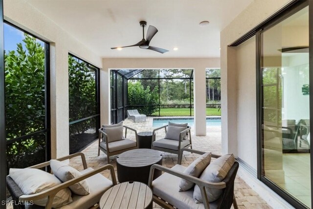 sunroom featuring ceiling fan and a pool