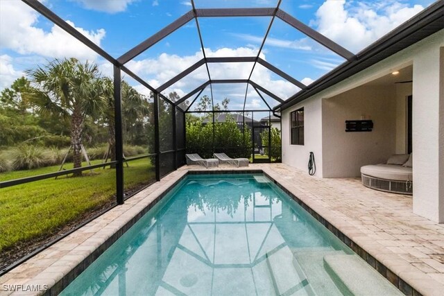 view of pool with a lawn, a lanai, and a patio area