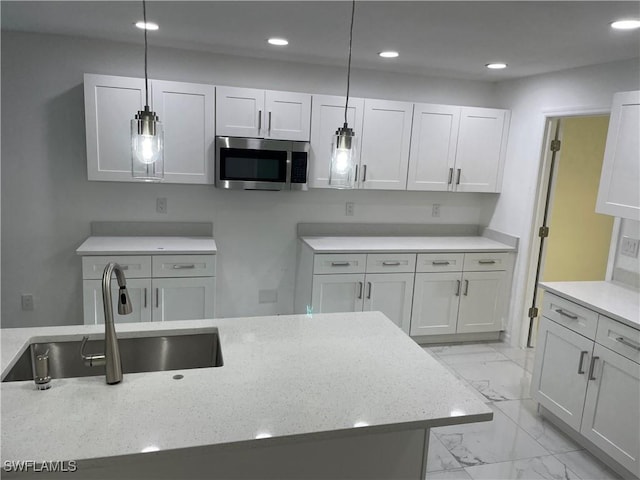 kitchen featuring light stone counters, sink, hanging light fixtures, and white cabinets