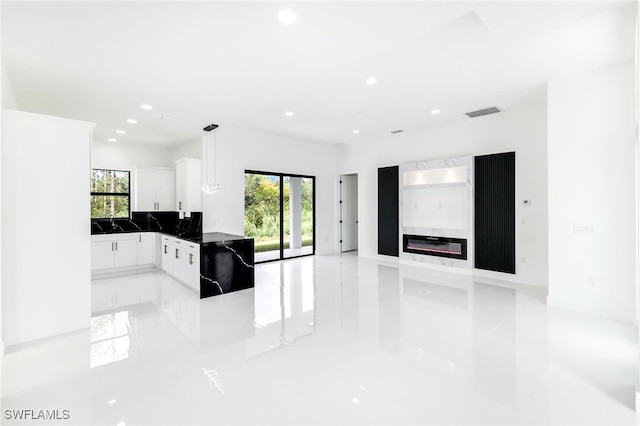 kitchen with sink, kitchen peninsula, hanging light fixtures, white cabinetry, and backsplash