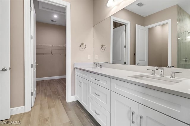 bathroom with hardwood / wood-style floors, vanity, and walk in shower