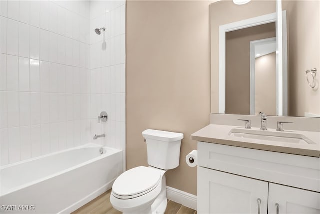 full bathroom with hardwood / wood-style floors, vanity, tiled shower / bath combo, and toilet