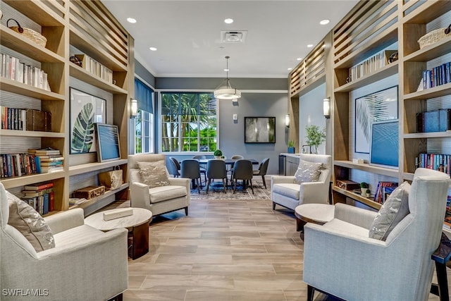 living area featuring built in features and crown molding