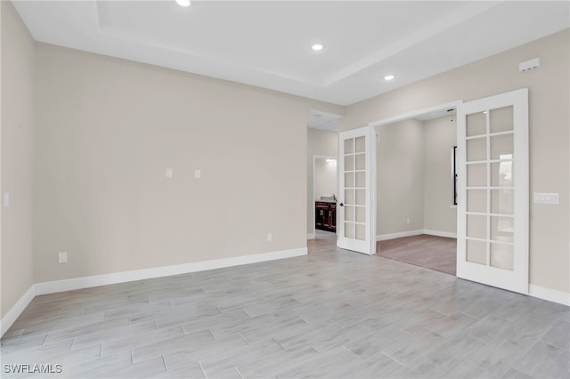 empty room with french doors and a tray ceiling