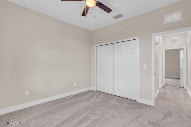 unfurnished bedroom featuring ceiling fan, a closet, and light carpet