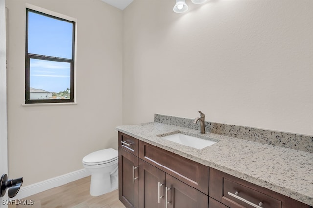 bathroom featuring hardwood / wood-style flooring, plenty of natural light, vanity, and toilet