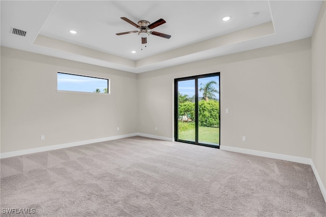 carpeted empty room featuring ceiling fan and a raised ceiling