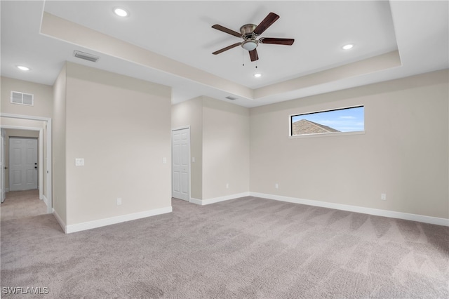 carpeted spare room featuring ceiling fan and a raised ceiling